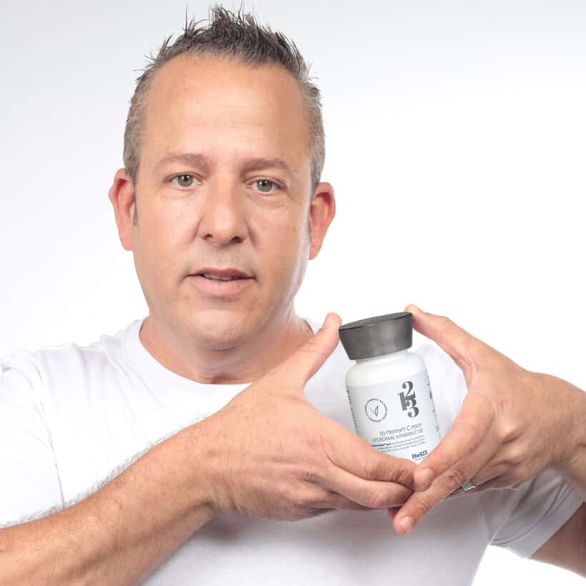 איש בגיל ביניים מחזיק בידיו בקבוק של תוסף תזונה ויטמין C ליפוזומלי 123 קפסולות liposomalix™pro