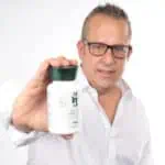 איש בגיל ביניים מחייך למצלמה כאשר הוא מחזיק בידו בקבוק תוסף תזונה מורינגה 123 קפסולות | מיצוי בריכוז 1:10