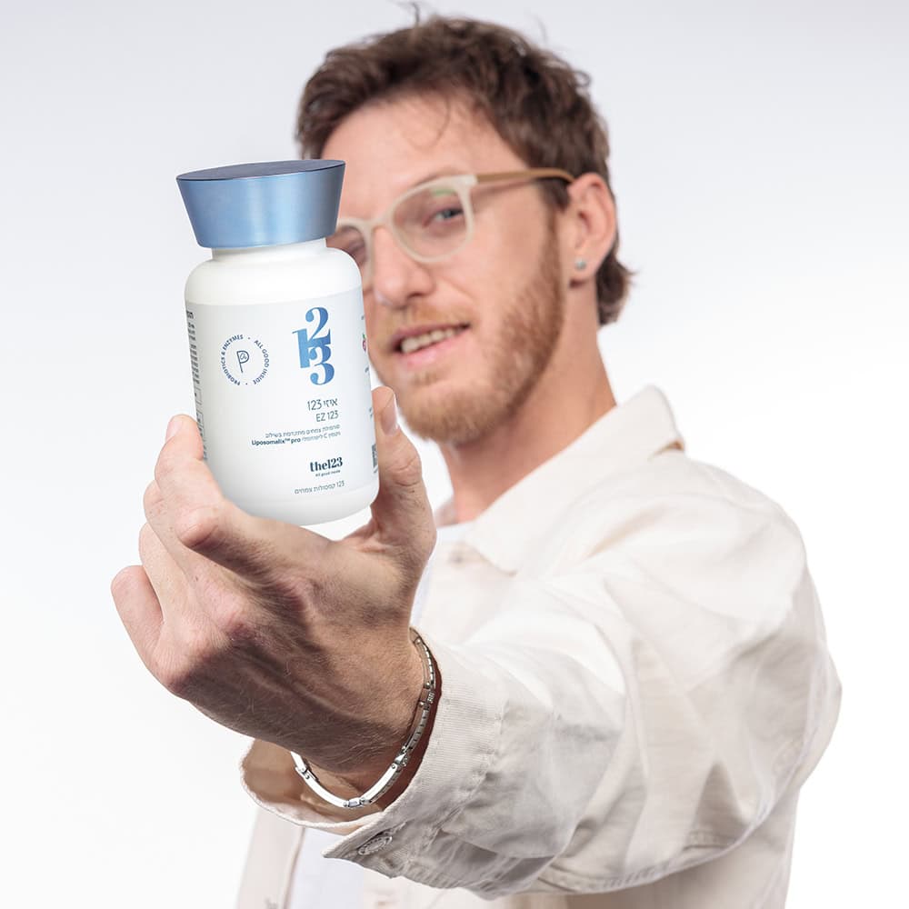 בחור מחייך מציג בקבוק של תוסף תזונה איזי 123